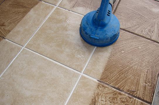 cleaning the dirty tiles using a blue cleaning equipment