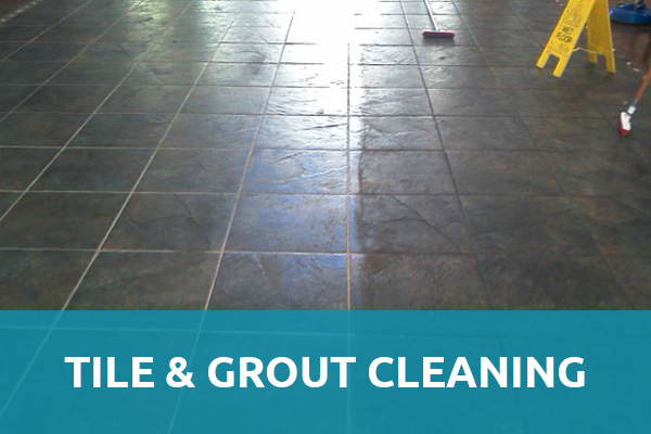 A ceramic floor tiles with grout with the sun reflection and along with the floor cleaning materials and a yellow floor sign caution and a header title that says "Tile & Grout Cleaning" and that is one of the services of carpet cleaning Albuquerque.